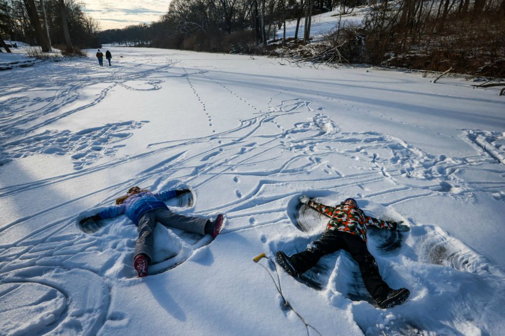 Feature - 3rd place - Bowling Green resident Leah Kaiser, 8, (left) and cousin Wadsworth resident Carter Cousino, 8, make snow angels on a frozen over Silver Lake at Side Cut Metropark in Toledo.  (Isaac Ritchey / THE BLADE/ISAAC RITCHEY)