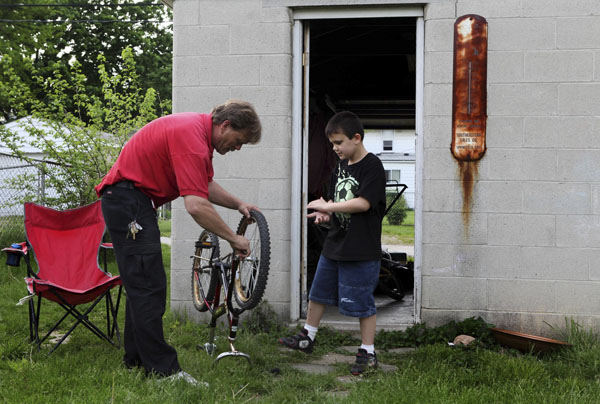 General News - 2nd place - Brian Sturgill (left) fixes a bike for his son Brandon at their west side home in Columbus. Brian is part of a new demographic of single parents raising children.  (Eric Albrecht / The Columbus Dispatch)