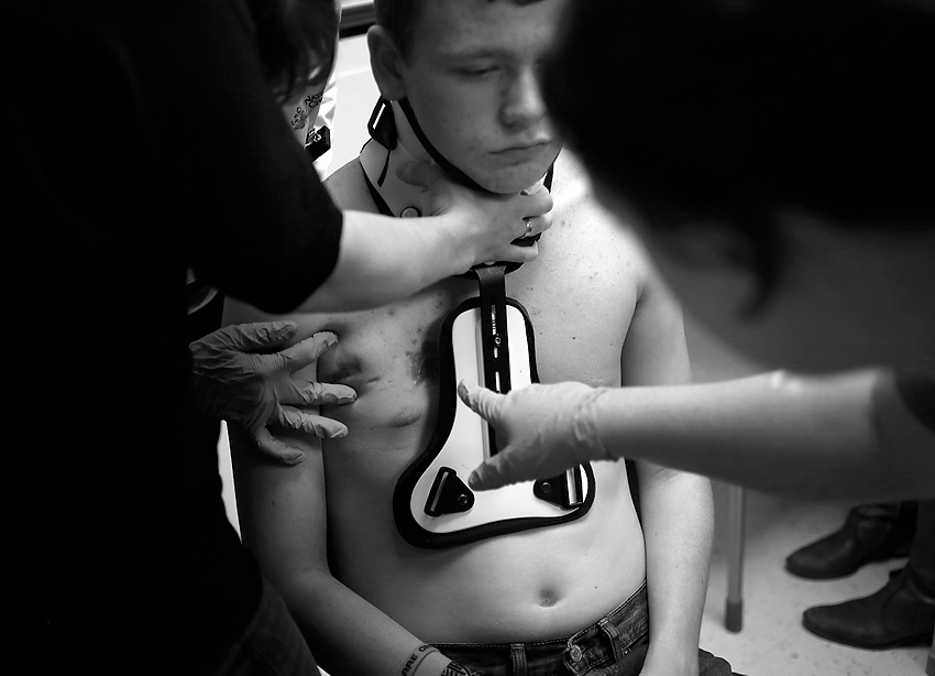 Second Place, Feature Picture Story - Jonathan Quilter / The Columbus DispatchSeventeen-year-old Logan Cole, who was shot twice by fellow student Ely Serna, 17, at West Liberty-Salem High School on January 20th, was having his wounds checked to see if he would need skin grafts soon. His mom was supporting his neck as they temporarily loosened his brace to get a better look at the area where the second shot missed his spinal cord by about the space of a thumb-tack head.  Ely Serna, a standout wrestler for the West Liberty-Salem High School Tigers in the 170-pound weight class, later confessed to authorities that he used the 12-gauge shotgun his grandparents had bought him one Christmas, fired the first of at least six rounds that morning into Logan who surprised him by walking into the bathroom where he was getting ready. Authorities said later that Logan likely threw off Ely's plan for whatever widespread destruction he sought to carry out at his high school.In this rural town of 1,788 the Serna and Cole families know each other and both were shocked to find out their children were involved.It is easy to chalk it up to chance that Logan was in that bathroom in that hallway at that moment on that day.But for the Coles -- parents Ryan and Julie and their seven children, including Logan -- it is no such thing."The amount of things that have lined up in a miraculous way that made this turn out to be not so bad. It's just … " Logan said, pausing. "It's God. That's the only explanation I can think of."Fifteen days in Nationwide Children's Hospital in Columbus fighting for his life. Three months wearing a neck and back brace to protect his damaged vertebrae. A potential lifetime of complications from the hundreds of lead birdshot still in his body that could slowly poison him. How can he call any of this a miracle?Logan, a junior who turned 17 last month, half-smiled and shrugged. He said simply: "Because I'm alive."