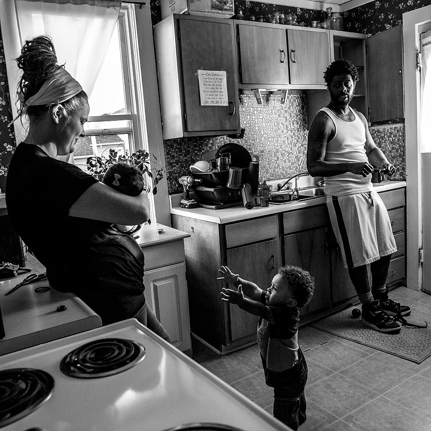 Third Place, Feature Picture Story - Jessica Phelps / Newark AdvocateDesmond and his wife DeeDee chat in the kitchen while she feeds their newborn baby, Rosalie in Newark. 'Lil Des", who has been the center of attention his whole life, fights to get some from his parents in this moment. 