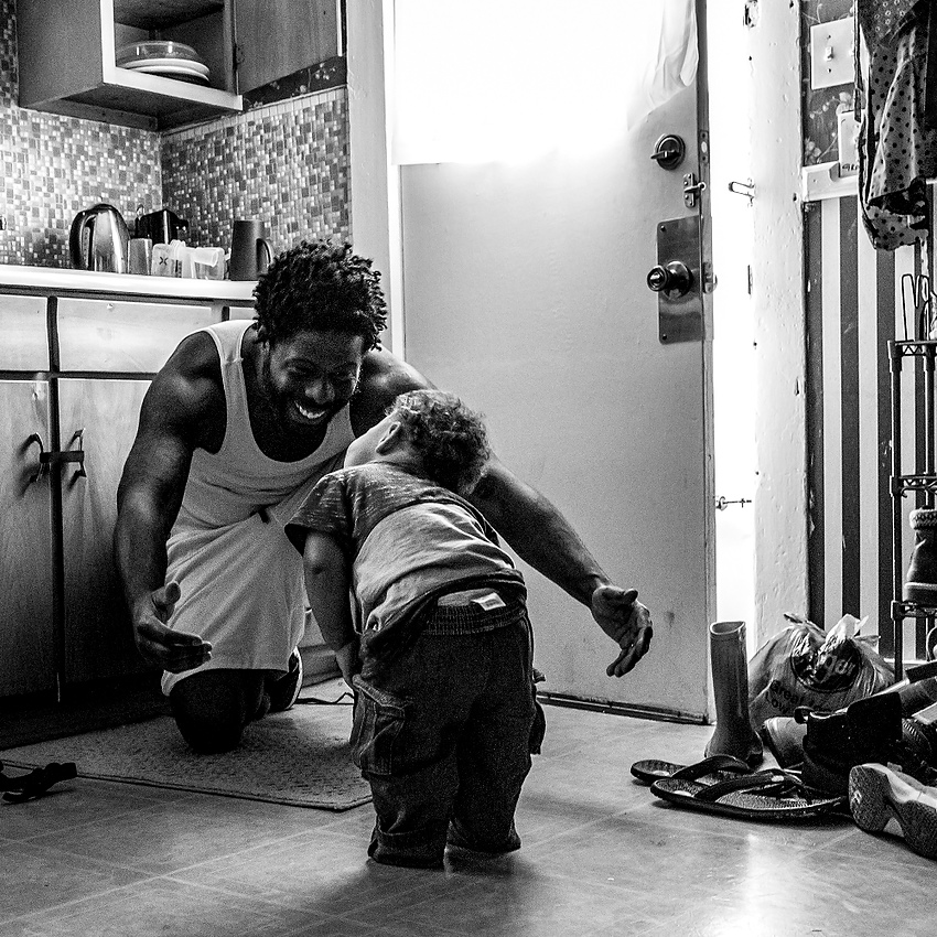 Third Place, Feature Picture Story - Jessica Phelps / Newark AdvocateDesmond Gordon holds his arms out and encourages his son to give him a hug in their Newark home. His son, Lil Des, spent his first months of life barreling towards everything but his father is trying to teach him to be gentle now that there is a new baby in the house.   
