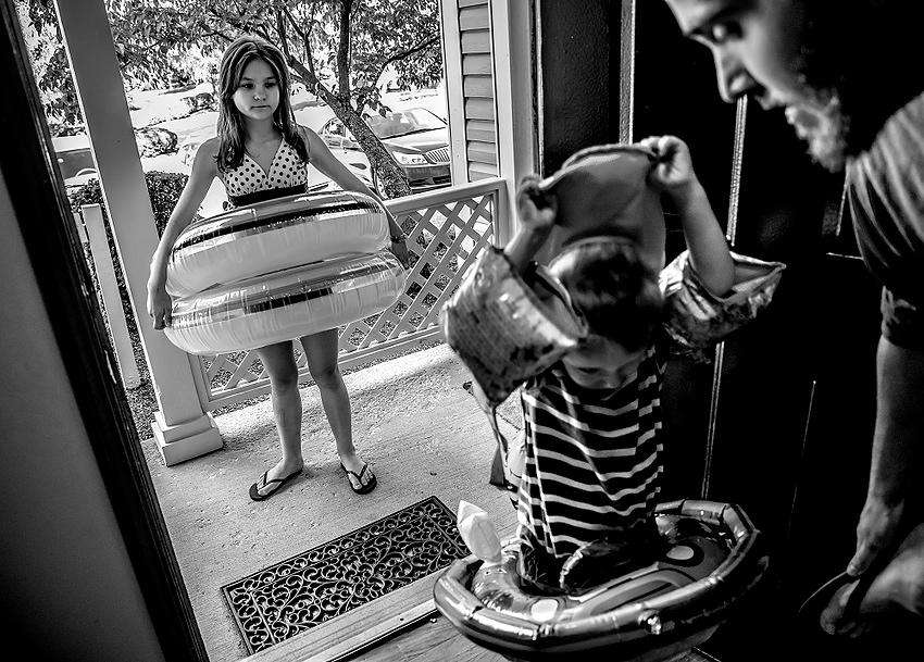 Award of Excellence, Feature Picture Story - Jessica Phelps / Newark AdvocateLera waits impatiently as her brother, Beau, and new father, Brett, fumble around with swimming toys before heading to the swimming pool in their apartment complex. Even though it was chilly outside, the kids who had just arrived in Ohio were desperate to go swimming. Their adoptive parents, Caity and Brett could not find a real reason why not, so they went off to swim on the cold water. 