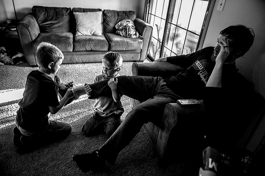 Award of Excellence, Feature Picture Story - Jessica Phelps / Newark AdvocateArcher and Beau put shoes on their new adoptive dad, Brett, before they leave for school. Brett and his wife Caity have loved being new parents, but are having trouble keeping up with the high energy levels of all four children. 