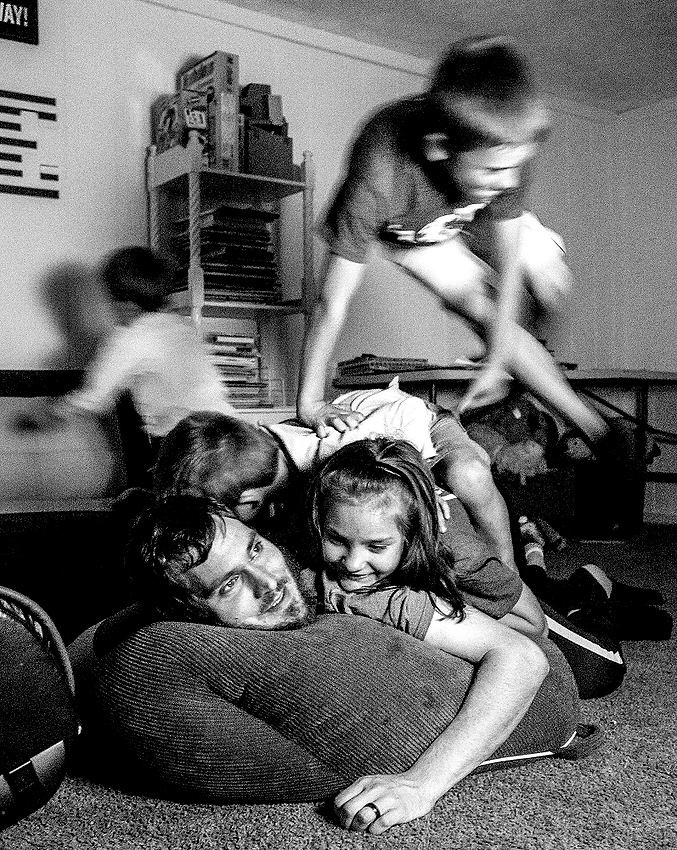 Award of Excellence, Feature Picture Story - Jessica Phelps / Newark AdvocateAll four kids, Lera, Max, Archer and Beau, use their new adoptive dad, Brett as a jungle gym in the basement of their new home. Brett and his wife, Caity, decided to adopt the siblings from the Ukraine after hosting three of them for the summer the year before. 