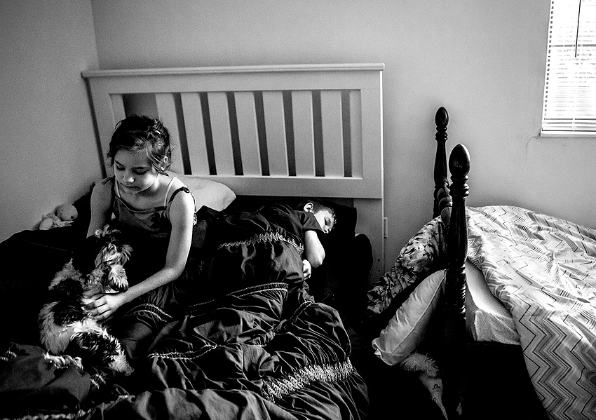 Award of Excellence, Feature Picture Story - Jessica Phelps / Newark AdvocateLera, plays with the family dog while her brother, Archer, struggles to wake up for school. Lera has had to sleep in the bed with her brother Archer, after she and her sibling got a little over-excited jumping on her bed, breaking it. 