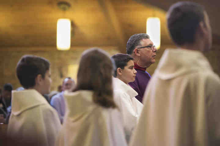 First place, Larry Fullerton Photojournalism Scholarsahip - Alexandria Skowronski / Ohio UniversityPastor James M. Daprile, of Youngstown kneels with his alter servers (from left) Peyton Duguay, Katie Sawicki, Zach Best, and Robert Lewandski, all from Aurora, during mass at Our Lady of Perpetual Help Catholic Church in Aurora.  Daprile has been pastor at the parish since January of 2011 and stays involved in the lives of many of its members.  (Alexandria Skowronski/Ohio University)