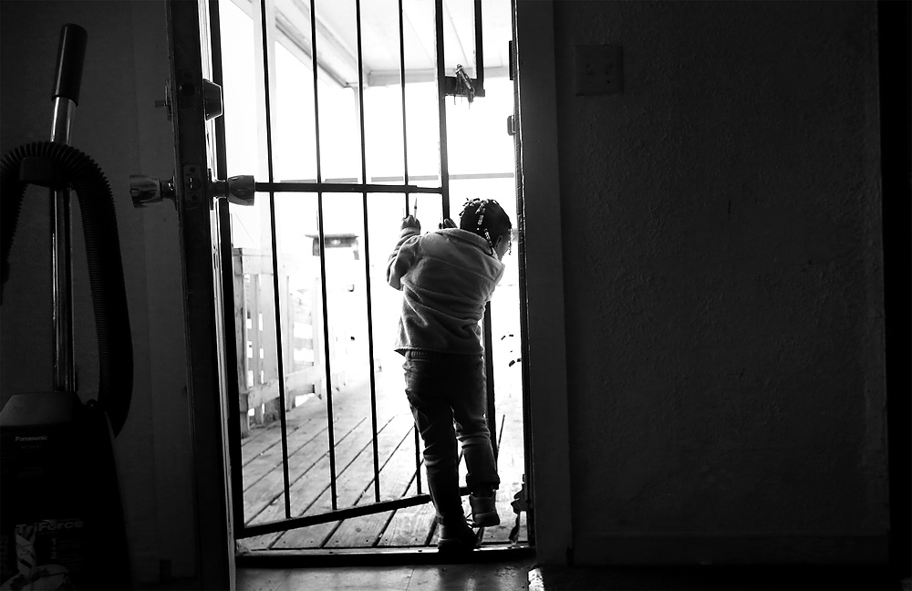 First Place, News Picture Story - Katie Rausch / The BladeMariah Gaston, 3, played with the security door at her grandmother's house in South Toledo. Mariah was diagnosed with lead poisoning at the age of one while living with her grandmother Mesha Wallace in the home the family continues to rent. Mariah was treated, and the family's landlord repainted the interior of the house. Ms. Wallace was alarmed to learn two years later that the Toledo-Lucas County Health Department had included her home on a list of houses unfit for human habitation due to lead contamination. With another grandchild, three-month-old Ozzie, living in their home Ms. Wallace said she had started working 60 hours a week in hopes of saving enough money to move. She is now having her three children and two grandchildren tested for lead.  