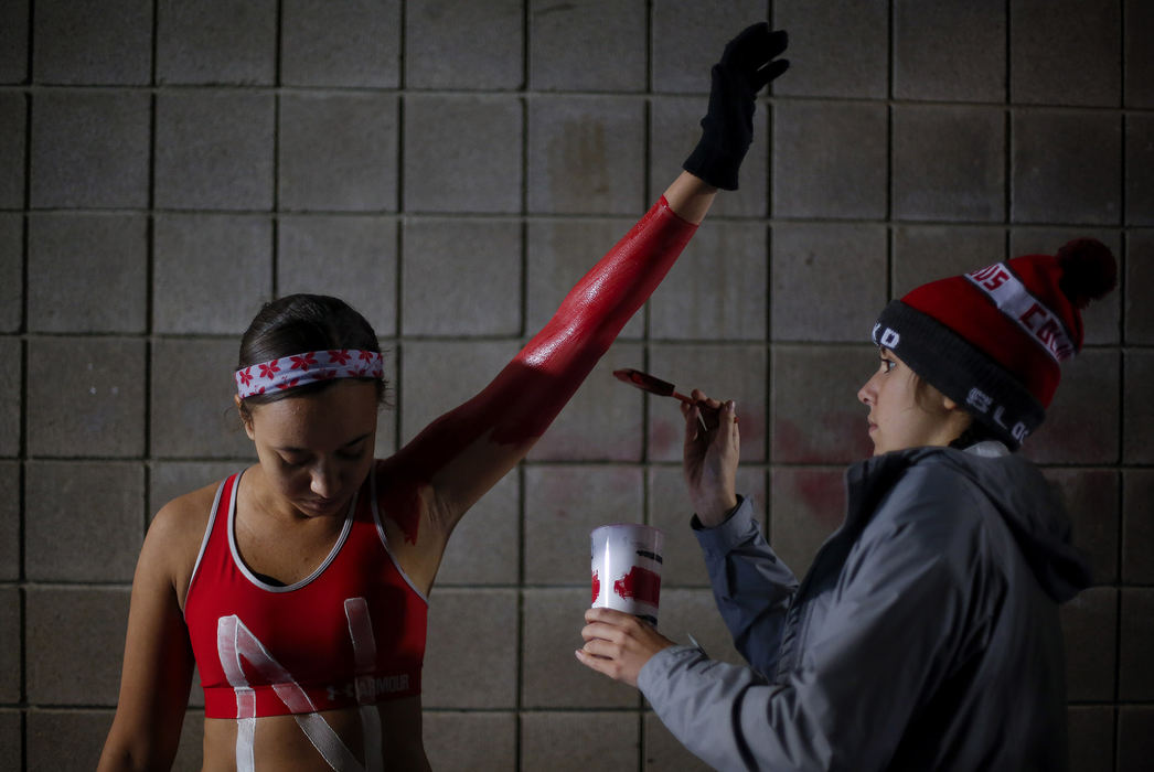 Ohio State freshman Bailey Mayes, left, raises her arm as freshman Alli Payne, right, applies body paint outside the Block O student section before a NCAA college football game between the Ohio State Buckeyes and the Illinois Fighting Illini on Saturday, November 18, 2017 at Ohio Stadium in Columbus, Ohio.