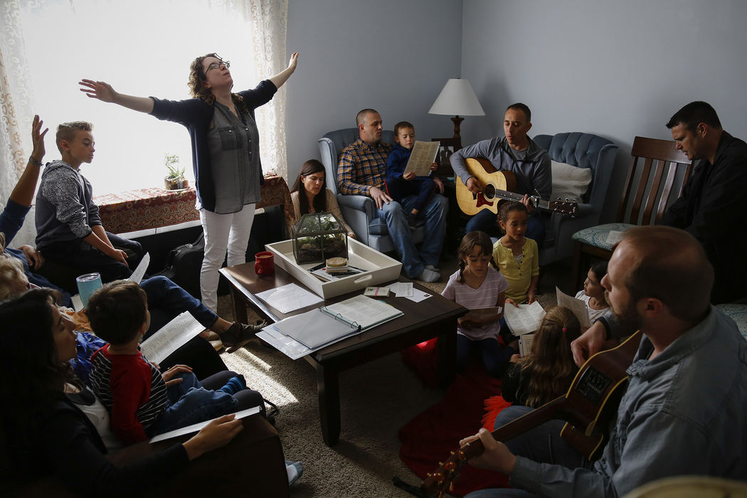 Erin Rollins raises her arms as she leads a song at the start of a worship service at her home on Sunday, April 23, 2017 in Dublin, Ohio. Rollins, along with her husband, Derrick, is a worship leader at Agathos, a non-denominational Christian church in the Short North. Members meet at the main church on the first and third Sundays of the month, and meet at a member's home on the second and fourth Sundays of the month. Members say "House Church" helps them form stronger relationships and a better understanding of scripture.