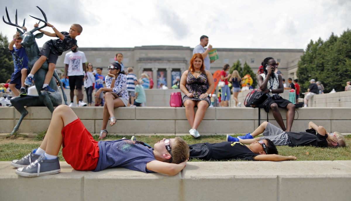 4th graders Ryan Steward, 9, left, Linden Marim, 9, center, and Drew Adamkosky, 9, right, from Oak Creek elementary in Olentangy watch the start of the solar eclipse during the COSI solar eclipse watch party in Columbus, Ohio on August 21, 2017.  