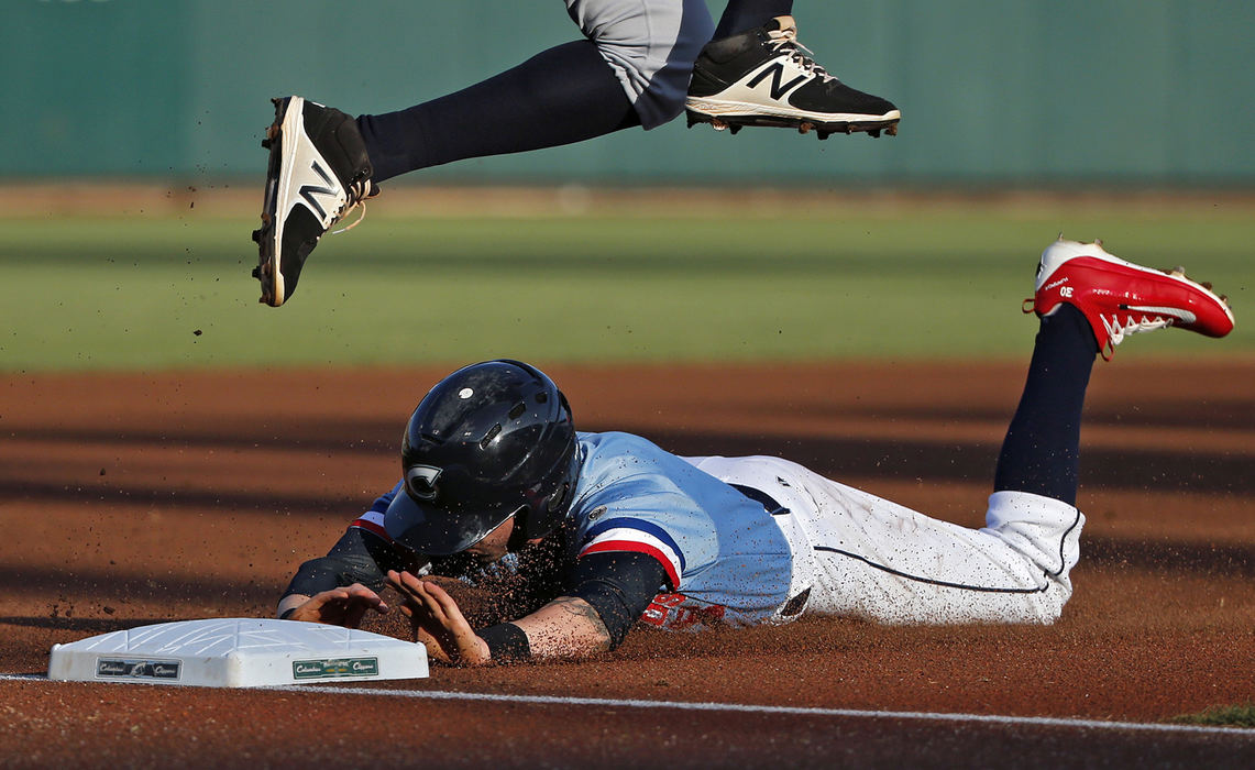 Columbus Clippers center fielder Tyler Naquin (6) steals a base at third base as Gwinnett Braves third baseman Carlos Franco (58) jumps over Naquin during their game at Huntington Park in Columbus on June 16, 2017.  