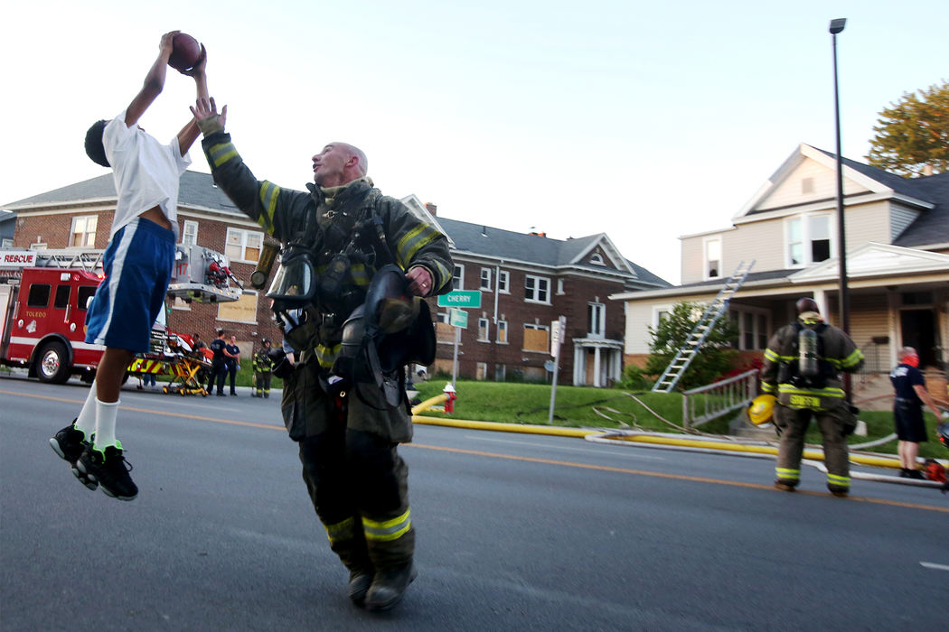 Lt. Pete Traver can't cover Tabari Triplett, 11, as he plays football with some friends from the neighborhood Monday, June 5, 2017, after Toledo firefighters had extinguished a blaze at a house on Cherry Street in Toledo. Battalion Chief Brent Wettle said the fire was reported at about 8:15 p.m. Monday evening in the 3300 block of Cherry Street, and caused an estimated $50,000 in damage. No injures were reported and the fire was under control within half an hour. The Red Cross was contacted to provide aid to seven residents of the house. 