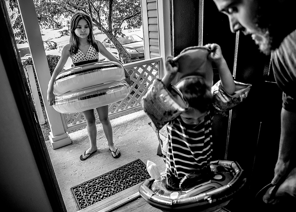 First Place, George S. Smallsreed Photographer of the Year  - Jessica Phelps / Newark AdvocateLera waits impatiently as her brother, Beau, and new father, Brett, fumble around with swimming toys before heading to the swimming pool in their apartment complex. Even though it was chilly outside, the kids who had just arrived in Ohio were desperate to go swimming. Their adoptive parents, Caity and Brett could not find a real reason why not, so they went off to swim on the cold water. 