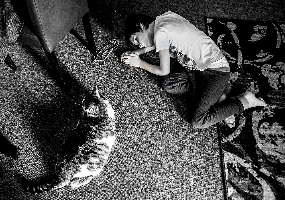 First Place, George S. Smallsreed Photographer of the Year  - Jessica Phelps / Jessica PhelpsTaven Lucterhand, 8, lays on the floor on August 14, 2017, and plays with his cat, Mishka, by pretending he is also a cat. Taven, who lives in Newark, Ohio, falls on the autism spectrum and often becomes enveloped in an idea for extended periods of time. He has always had a fascination with cats and can often be found crawling on the floor meowing. 