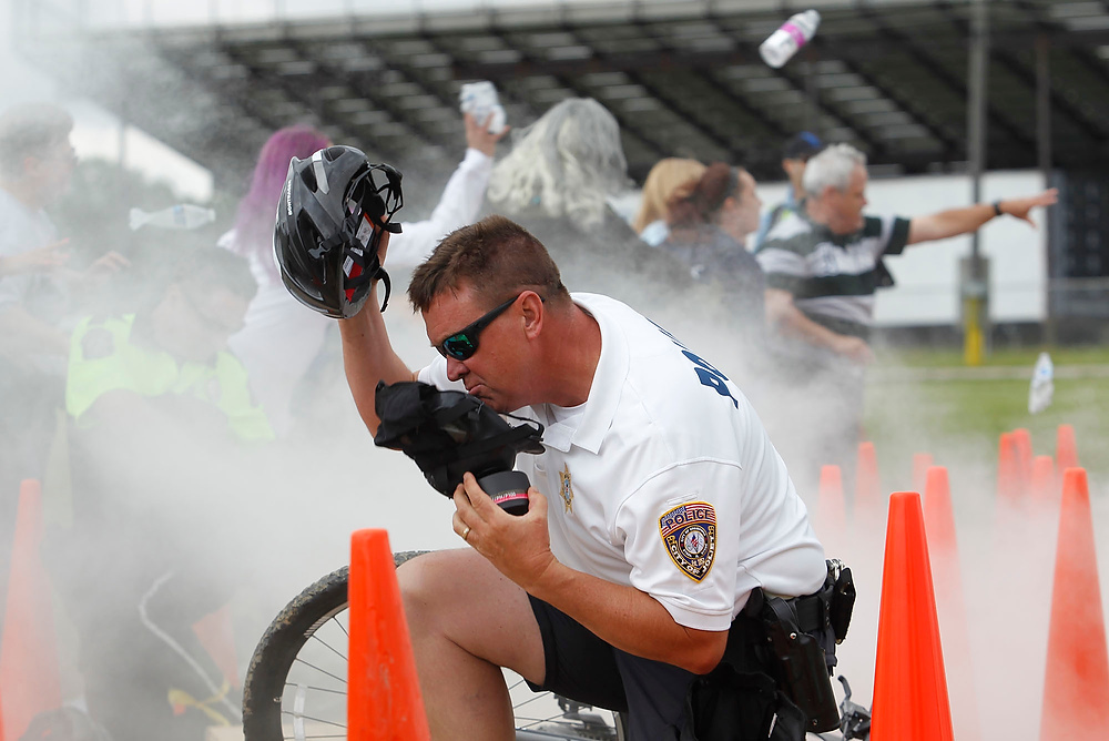 Second Place, George S. Smallsreed Photographer of the Year  - Lorrie Cecil / ThisWeek Community NewsSgt. Larry Collins with the Joliet Police Department puts his protective mask on as zombie hurl bottles at police during the International Police Mountain Bike Conference's crowd control exercise at the Delaware County Fairgrounds on Wednesday June 7.  As part of the exercise volunteers, mostly dressed as zombies, played an unruly crowd that the officers had to contain.  Officers from around the country and Canada participated in the event.  