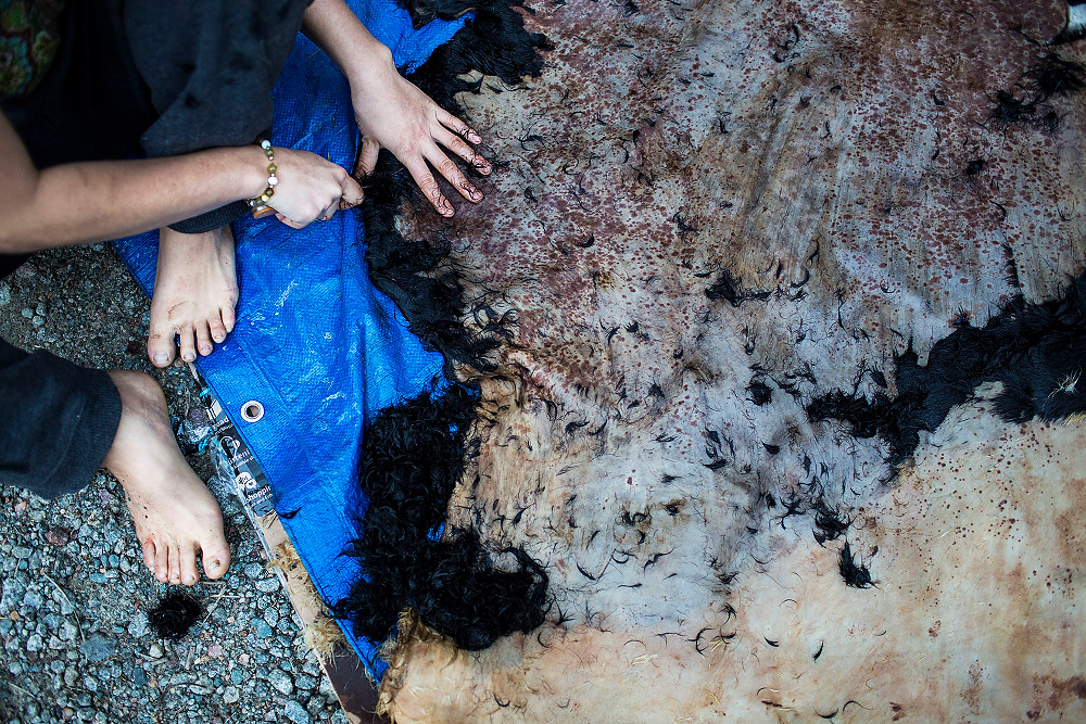 First Place, Chuck Scott Student Photographer of the Year - Erin Clark / Ohio UniversityJeli scrapes hair off of a cow hide after soaking the skin in a chemical cream. Jeli plans to use the hide to create shoes for community members.