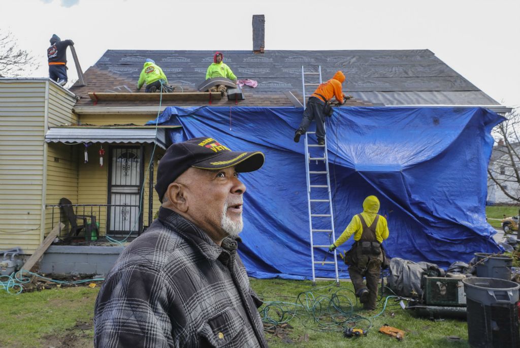 April - General News - 1st place - Veteran Glenn Walker stood in his front yard  and watched as a roofing crew layered rows of new brown asphalt shingles on top of his 124-year-old North Toledo home."I'm feeling good, I'm feeling good," said Mr. Walker, 69, the remnants of the old roof strewn around him. "You know how long it's taken me to get this. ... It's a blessing." Mr. Walker and his wife, Sheila, struggled a long time to figure out how to get a new roof. They dreaded big rainstorms, which would often trigger multiple leaks inside their small yellow home on St. John Avenue. Mr. Walker got his new roof installed with aid of the Lucas County Veterans Service Commission in Toledo.  (Jeremy Wadsworth / The Blade)