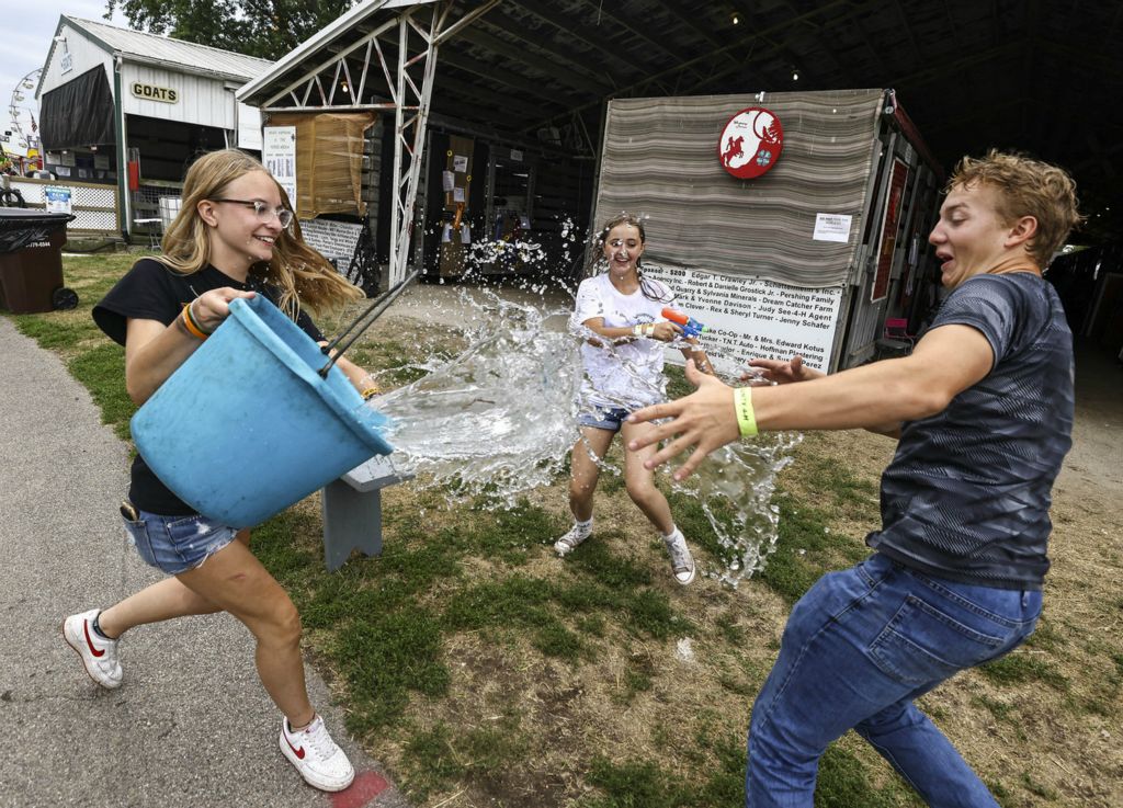 August - Feature - 1st place - From left Tatum Weakly, 16, of Monroe escalates a water gun fight with a bucket of water along with her friends Elizabeth Gomez, 15, of Huron and Ethan Layton, 16, of Dundee at the Monroe County Fair in Monroe, Michigan.   (Jeremy Wadsworth / The Blade)
